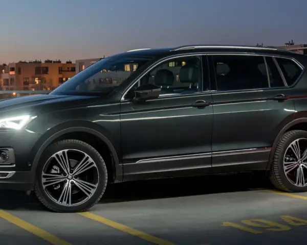 Ciemnozielony SUV z siedmioma miejscami stoi na parkingu nocą, z widokiem na budynki mieszkalne.