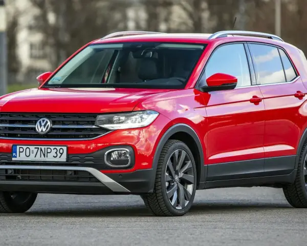 Czerwony, używany Volkswagen T-Cross z polskimi tablicami rejestracyjnymi PO 7NP39 stoi na drodze.