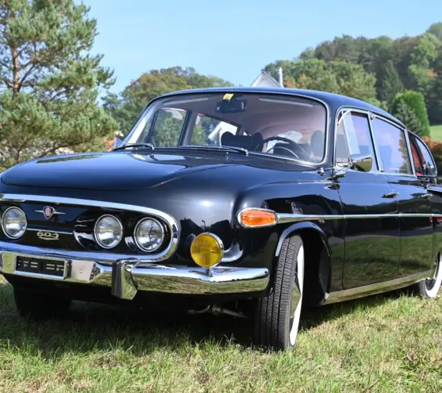 Czarna Tatra 603 lśni na trawie, gotowa na przejażdżkę.