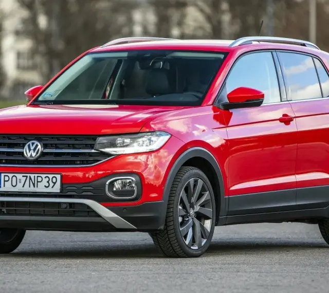 Czerwony, używany Volkswagen T-Cross z polskimi tablicami rejestracyjnymi PO 7NP39 stoi na drodze.