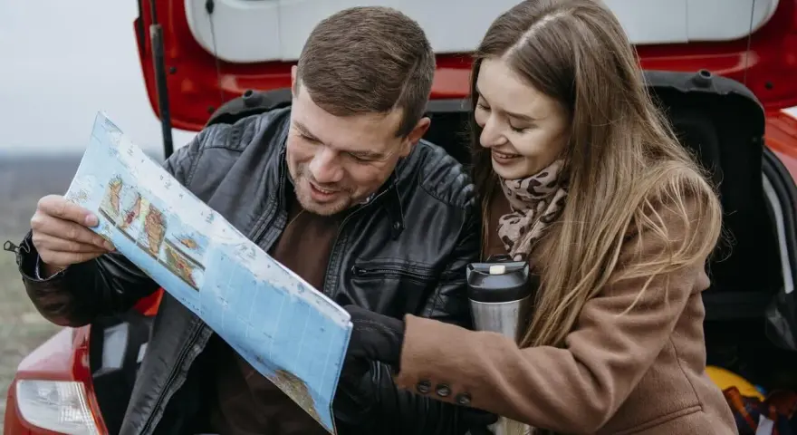 Para planować podróż i ubezpieczenie samochodu na wyjazd za granicę, para przegląda mapę.