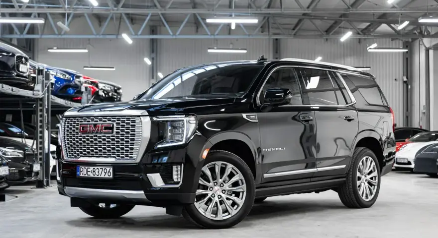 Czarny GMC Yukon Denali lśni w salonie samochodowym, gotowy na przygodę.
