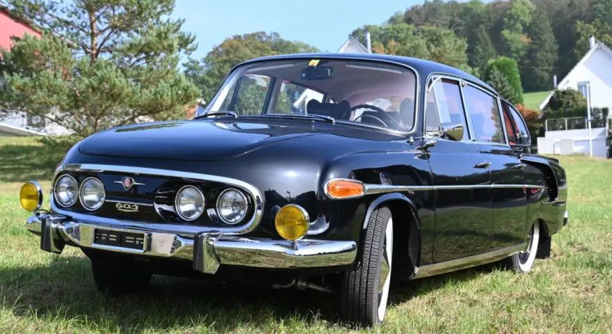 Czarna Tatra 603 lśni na trawie, gotowa na przejażdżkę.