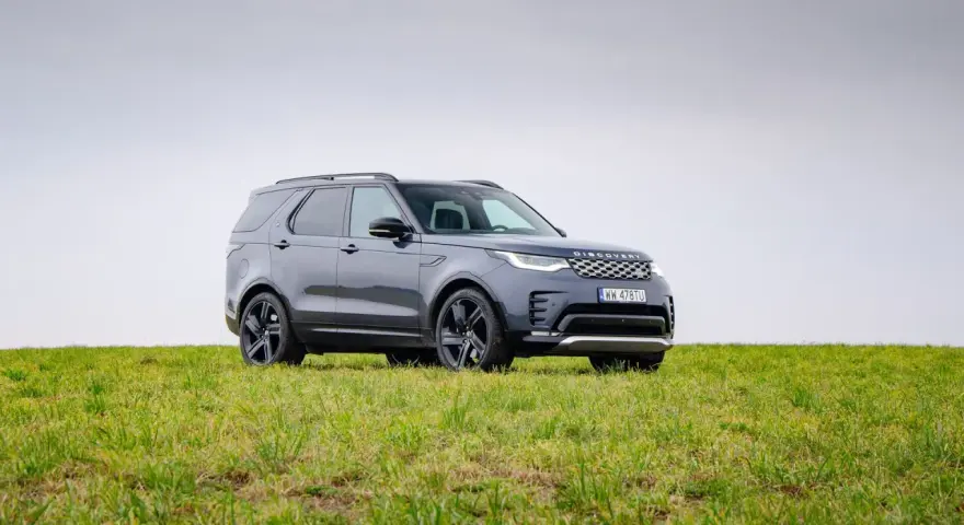 Szary Land Rover Discovery stoi na zielonej łące.