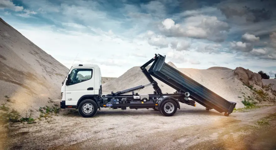Biały Mitsubishi Canter z podniesioną skrzynią ładunkową na tle żwirowych hałd.