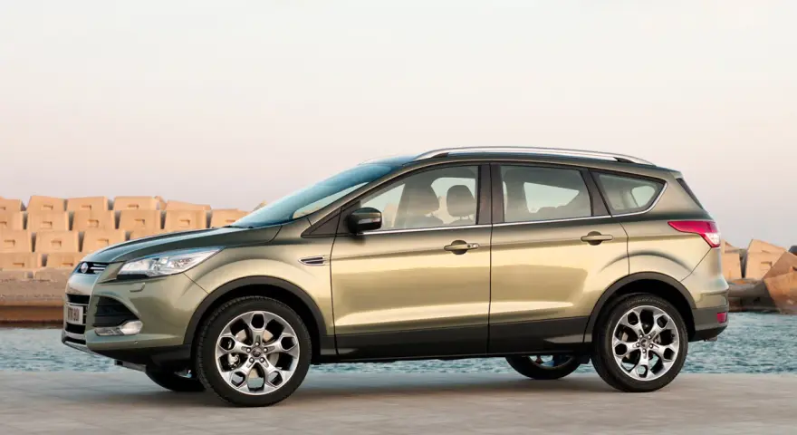 Złoty SUV Ford Kuga stoi na nabrzeżu przy morzu.