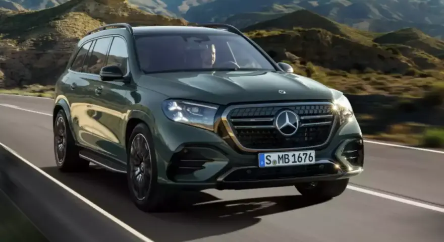 Zielony Mercedes GLS 580 pędzi po krętej drodze wśród gór.