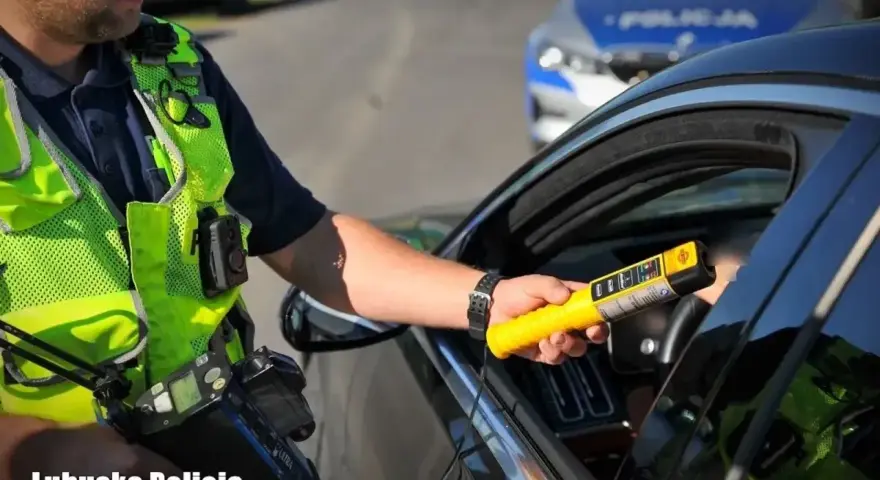 Policjant z Lubuskiej Policji bada kierowcę alkomatem. Za jazdę po alkoholu, nawet 1 promil, prawo jazdy jest zabierane.