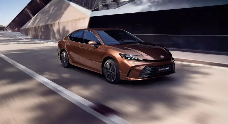 Brązowa Toyota Camry Hybrid w ruchu. Sprawdź aktualną toyota camry cena i wybierz swój wymarzony model.