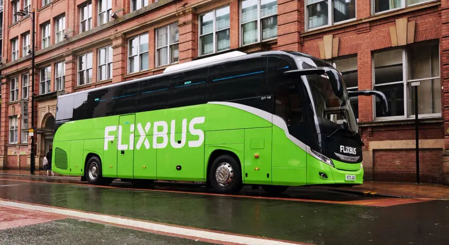 Zielony autokar FlixBus na mokrej ulicy. Wiele osób chwali sobie podróże tymi autobusami, a flixbus opinie są zazwyczaj pozytywne.