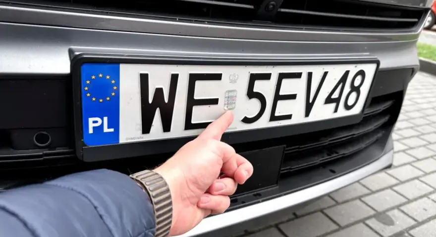 Palec wskazuje hologram na tablicy rejestracyjnej. Zastanawiasz się, ile kosztują tablice rejestracyjne?