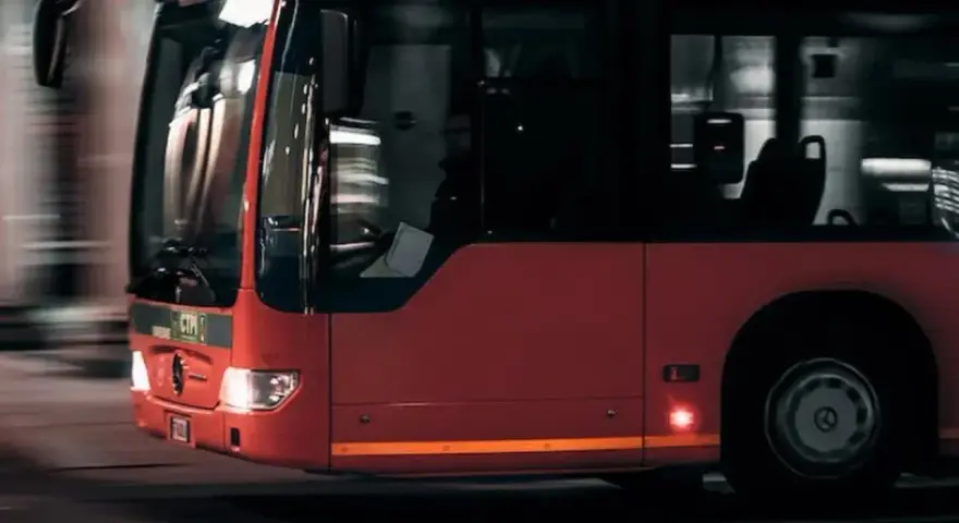 Czerwony autobus w ruchu miejskim, widok z przodu i z boku.