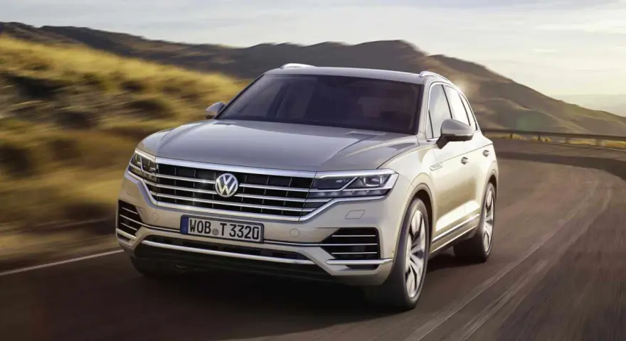 Elegancki Volkswagen Touareg, jeden z wielu imponujących volkswagen modele, pędzi po krętej drodze wśród wzgórz.