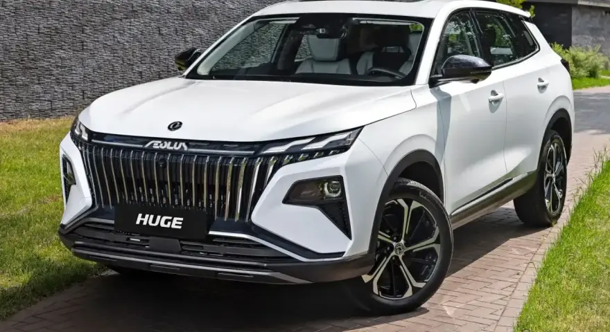 Nowy, biały chinski suv z imponującym grillem i felgami stoi na podjeździe.