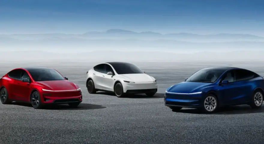 Trzy samochody Tesla: czerwony, biały i niebieski, stoją na pustej drodze z górami w tle.