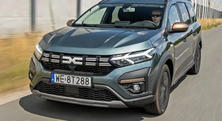 Dacia Jogger w zielonym kolorze jedzie po drodze. Sprawdź atrakcyjną dacia jogger cena i wybierz swój wymarzony samochód.