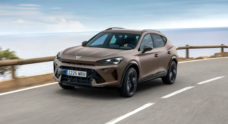 Brązowy SUV Cupra jedzie po drodze nad morzem.