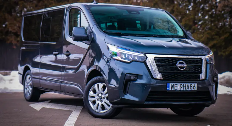 Ciemnoszary Nissan NV300 z nowoczesnymi światłami LED stoi na parkingu.