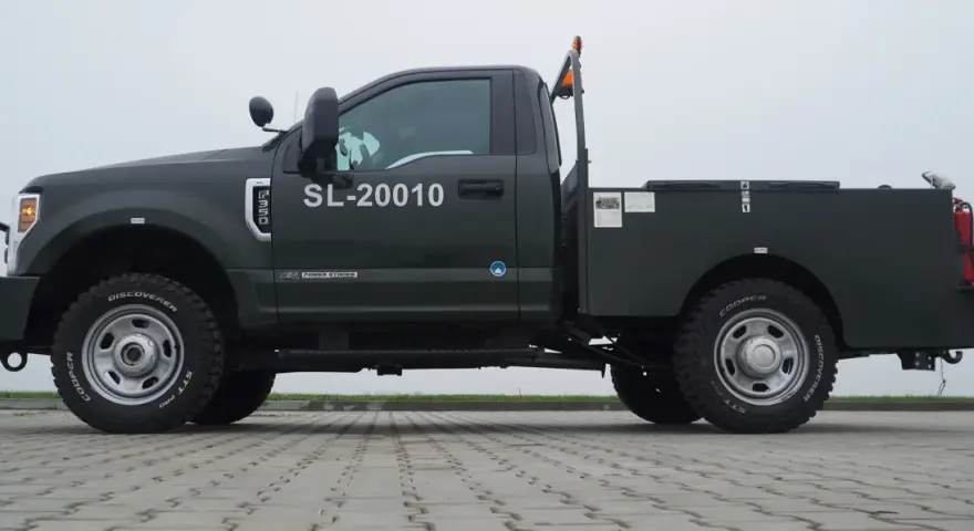 Ciemnozielony Ford F350 z zabudową typu "flatbed" i numerem SL-20010. Solidna maszyna gotowa do pracy.