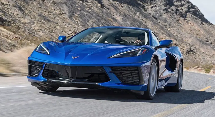 Błękitny Chevrolet Corvette Stingray pędzi po pustynnej drodze.
