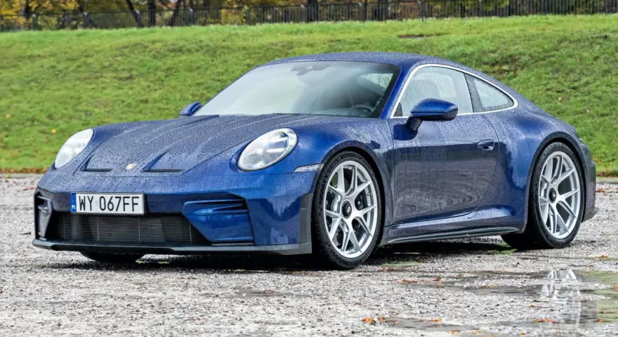 Niebieskie Porsche 911 na mokrej nawierzchni. Zastanawiasz się nad porsche 911 cena? Ten model zachwyca.