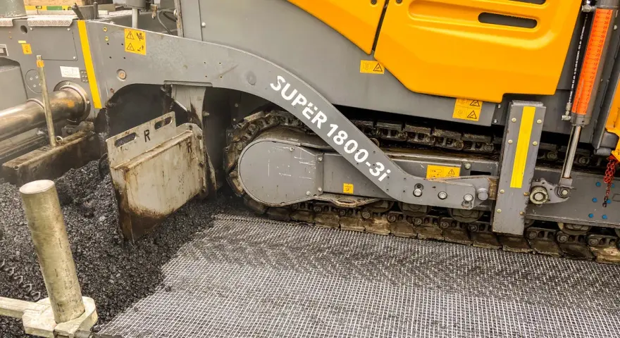 Asfaltarka w akcji, układająca nawierzchnię drogową.