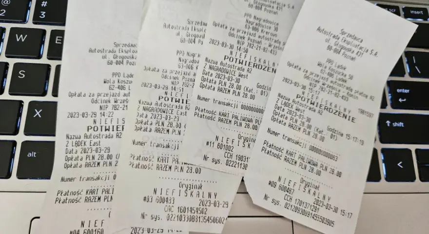 Paragon fiskalny z autostrady A2 na klawiaturze laptopa.