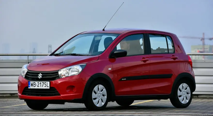 Czerwony Suzuki Celerio z polskimi tablicami rejestracyjnymi WB 2175L zaparkowany na zewnątrz.