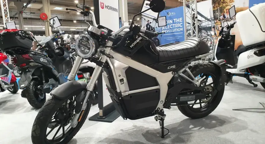 Czarny motocykl elektryczny Horwin CR6 na wystawie, obok innych skuterów.