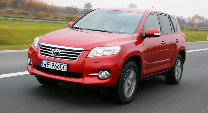 Czerwony SUV do 30 tys. na drodze, z widocznym grillem i tablicą rejestracyjną WE 966EC.