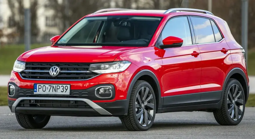Czerwony, używany Volkswagen T-Cross z polskimi tablicami rejestracyjnymi PO 7NP39 stoi na drodze.