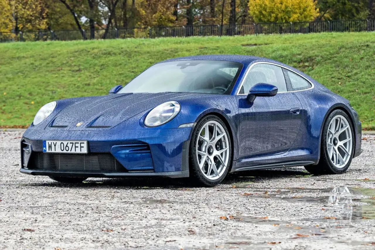 Niebieskie Porsche 911 na mokrej nawierzchni. Zastanawiasz się nad porsche 911 cena? Ten model zachwyca.