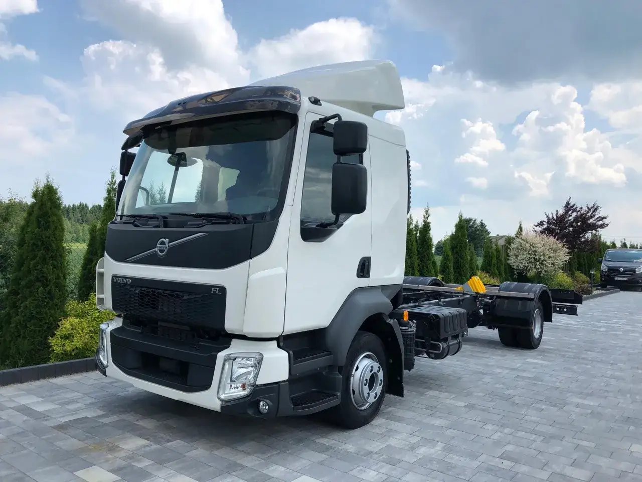 Biały Volvo FL bez zabudowy, gotowy do pracy. Czekał na montaż nadwozia pod błękitnym niebem.