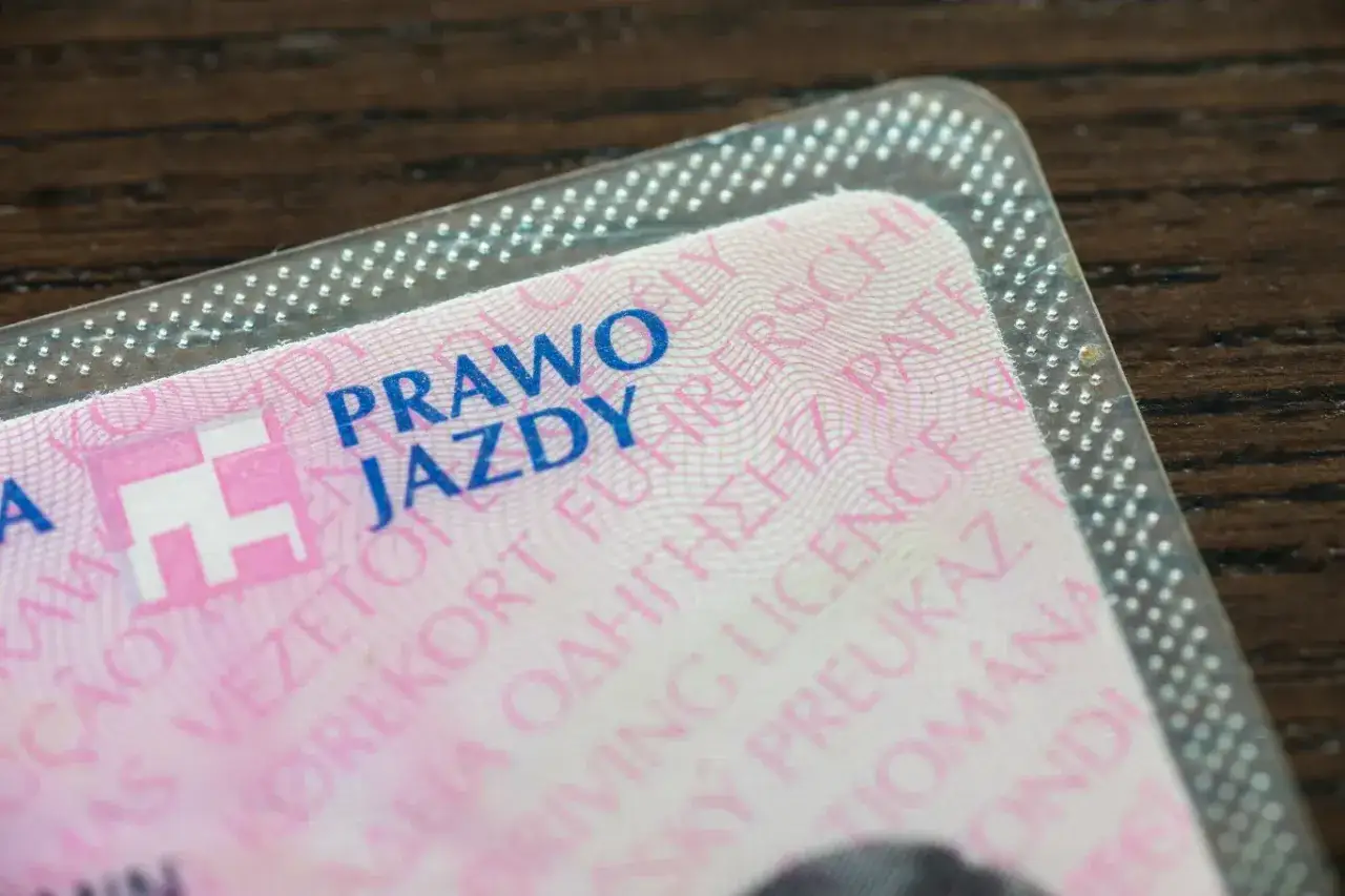 Zbliżenie na polskie prawo jazdy, symbolizujące wymianę dokumentu po ślubie. Widoczne napisy w różnych językach.