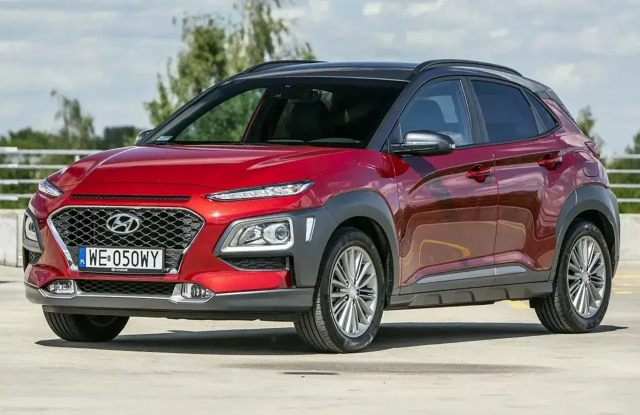 Czerwony, mały SUV Hyundai Kona z czarnym dachem, zaparkowany na zewnątrz.