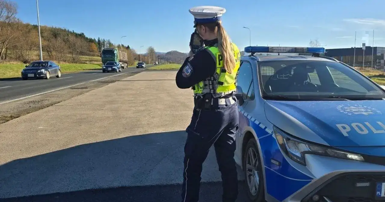 Policjantka mierzy prędkość radiowozem, by ukarać kierowców punktami karnymi za przekroczenie limitu.