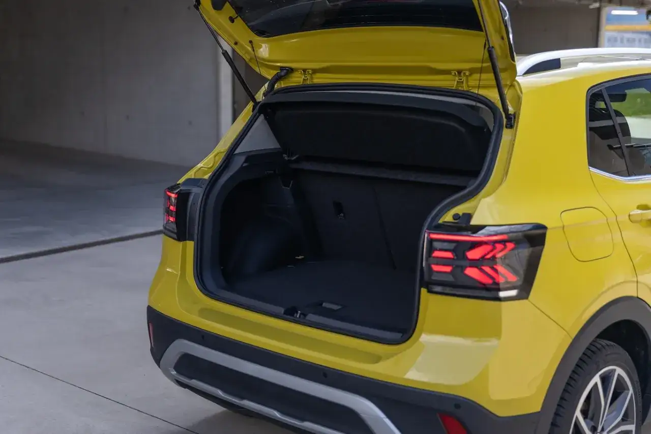 Żółty Volkswagen T-Cross używany z otwartym bagażnikiem. Idealny na rodzinne wycieczki i zakupy.