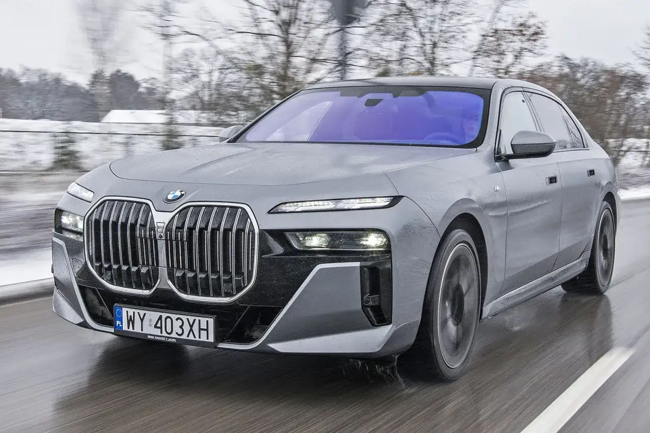 Szary BMW Serii 7 w ruchu, z widocznym grillem i reflektorami. Sprawdź aktualną bmw 7 cena.
