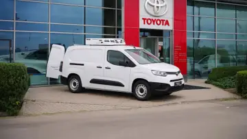 Biały, mały dostawczak z chłodnią na dachu stoi przed salonem Toyoty.