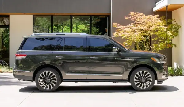 Ciemnoszary Lincoln Navigator SUV zaparkowany przed nowoczesnym domem z drzewem klonu japońskiego.