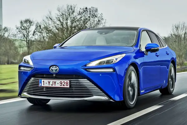 Niebieska Toyota Mirai jedzie po drodze. Sprawdź aktualną toyota mirai cena i dowiedz się więcej o tym innowacyjnym samochodzie.