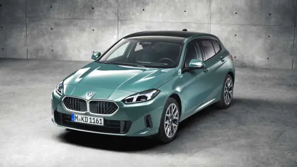 Nowy, zielony bmw hatchback z czarnym dachem, zaparkowany na betonowym podłożu.