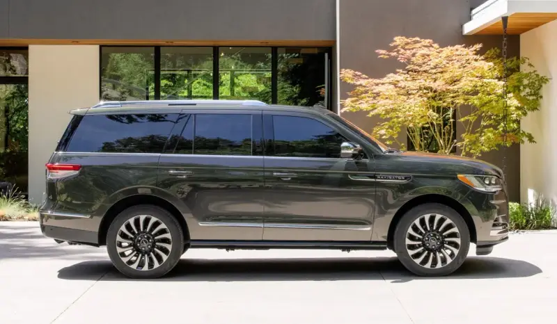 Ciemnoszary Lincoln Navigator SUV zaparkowany przed nowoczesnym domem z drzewem klonu japońskiego.