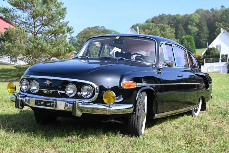 Czarna Tatra 603 lśni na trawie, gotowa na przejażdżkę.